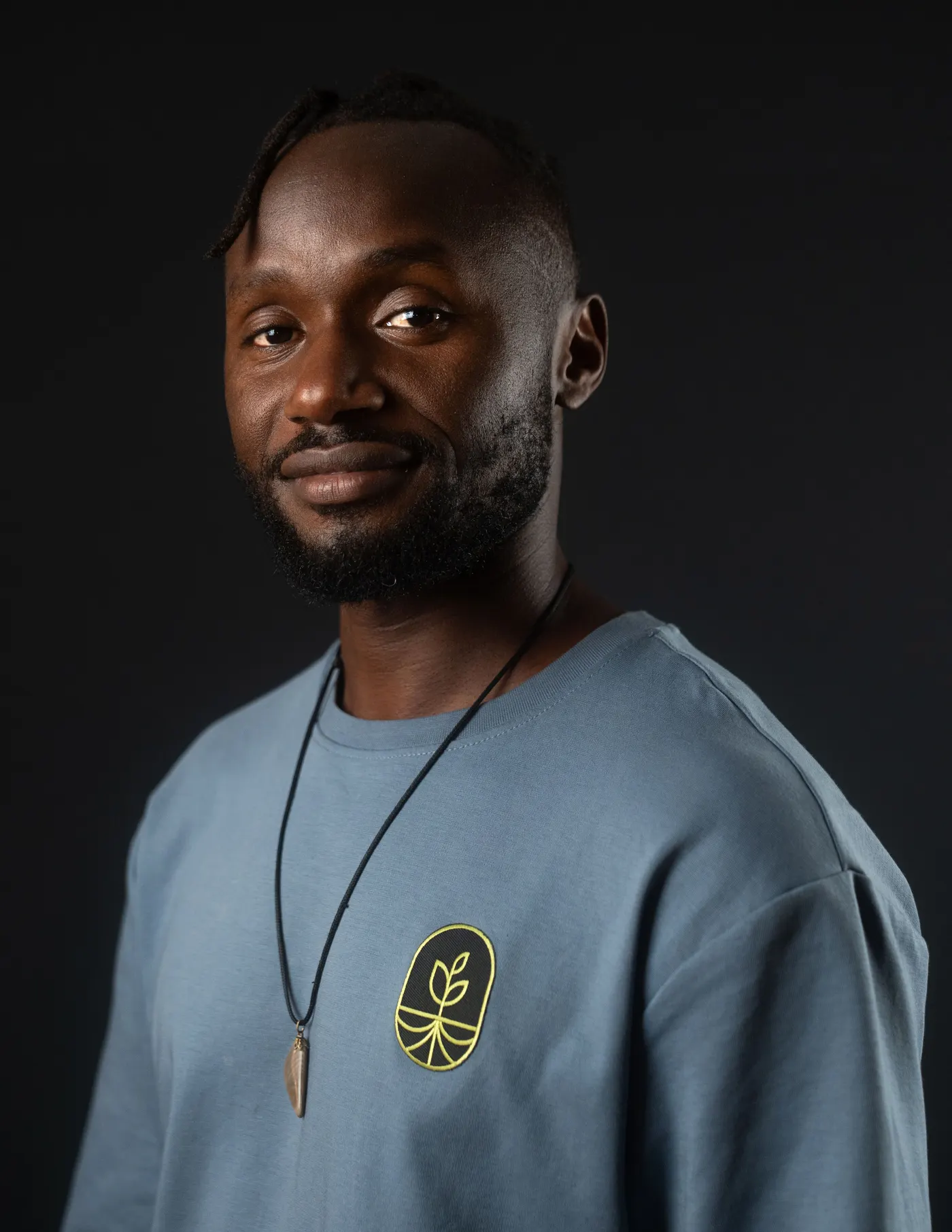 Pierre Semudenge in een blauw shirt met het Voetbal Dream Coach logo, tegen een donkere achtergrond